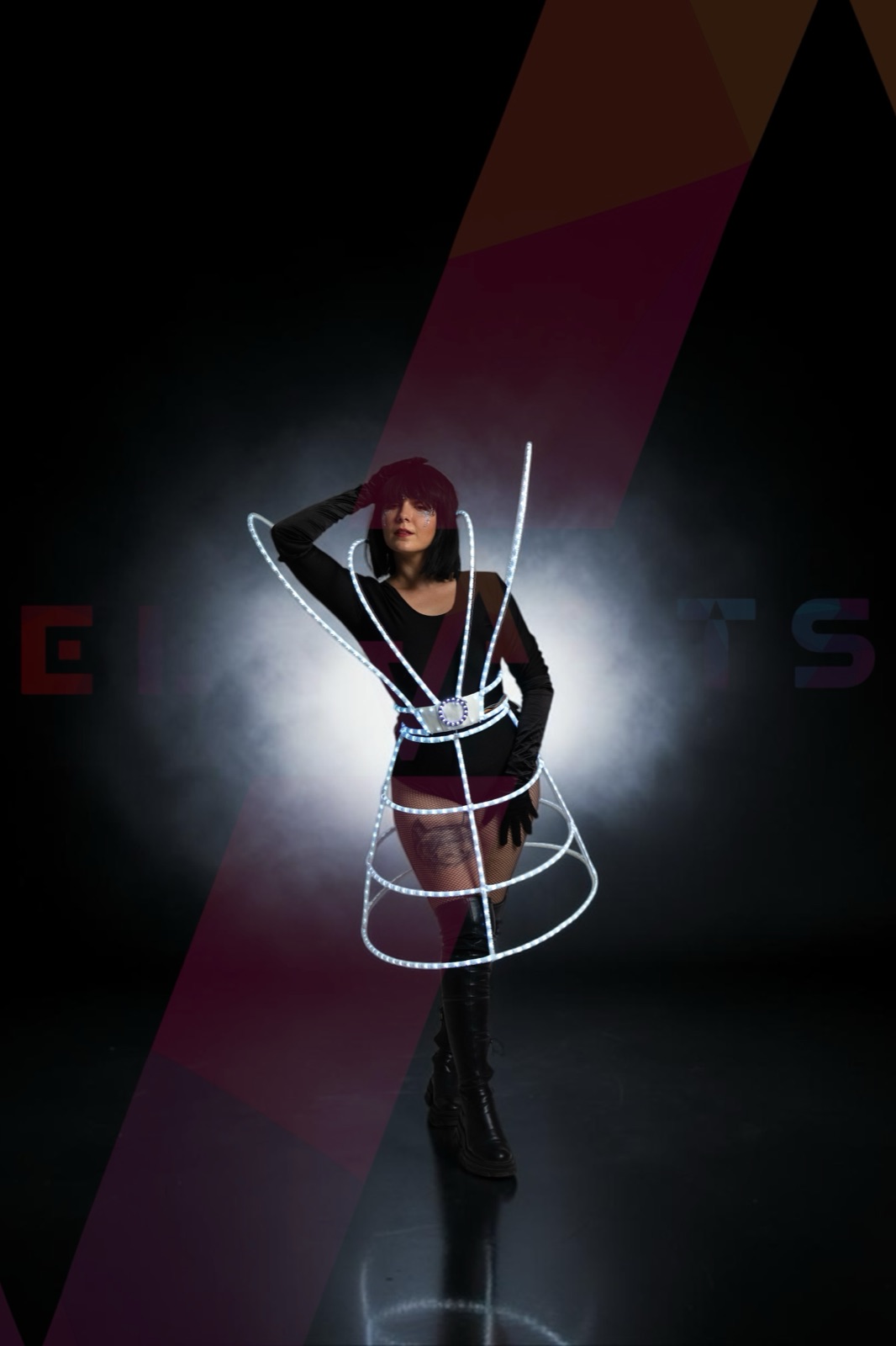 Performer in an addressable-LED corset and hooped skirt, lit white against a dark stage