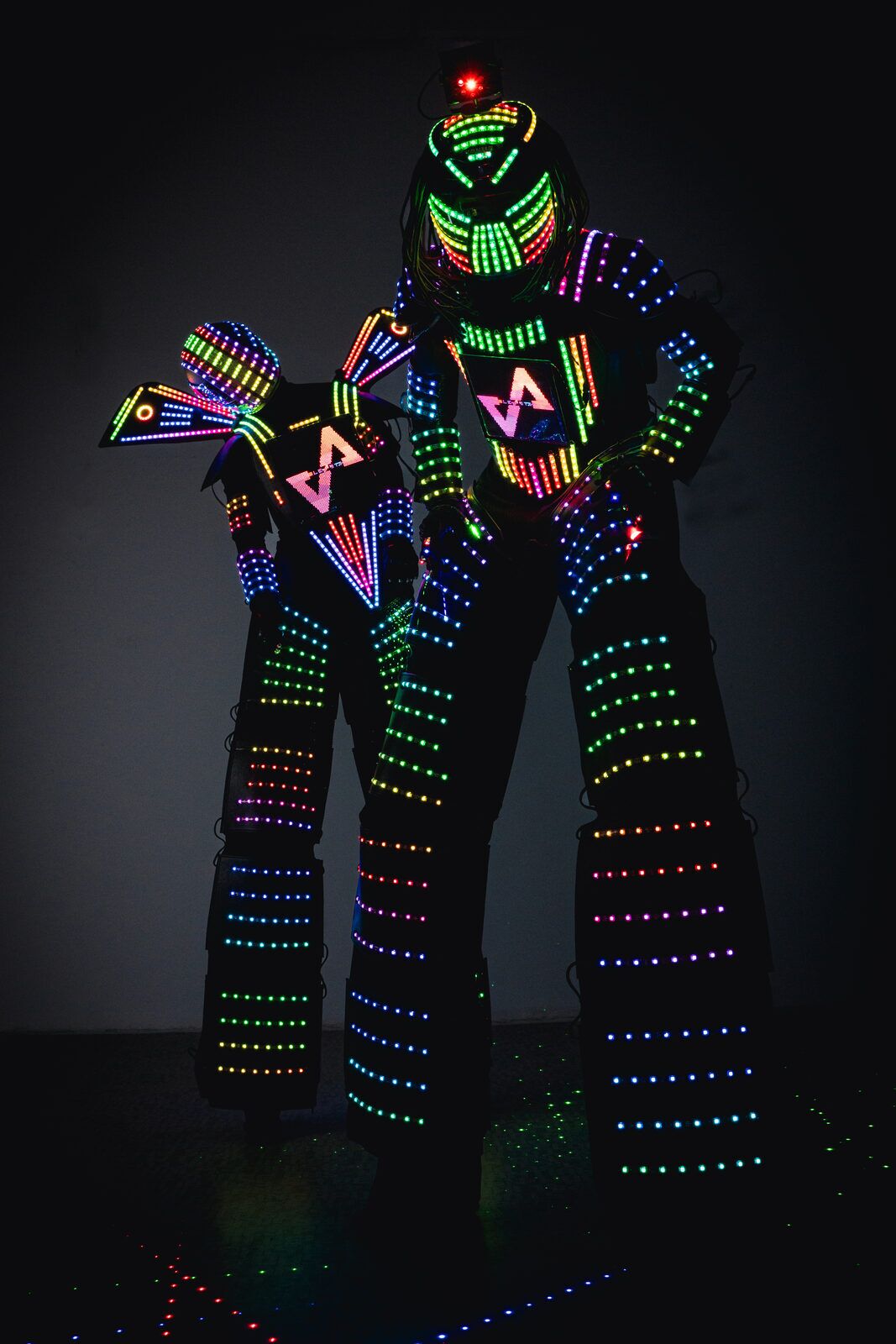 EleVArts LED robot suit on stilts, full-body addressable LEDs lit in rainbow, programmable chest screen glowing